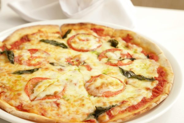 Delicious Margherita pizza topped with fresh tomatoes, mozzarella, and basil on a white plate.